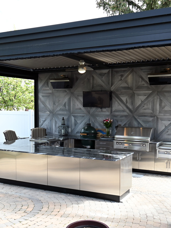 outdoor kitchen with grills and a tv